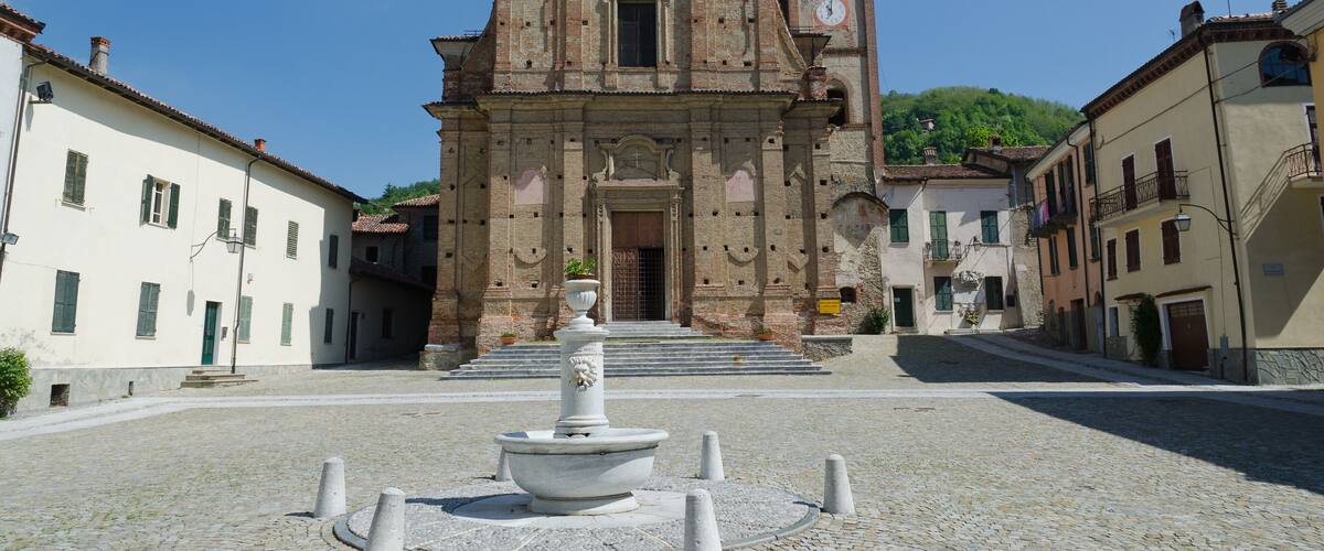 A historic church with a bell tower and a fountain in the center of a cobblestone square.