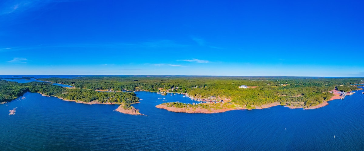 An aerial view of a coastal region with a large body of water, several small islands, and dense forests.