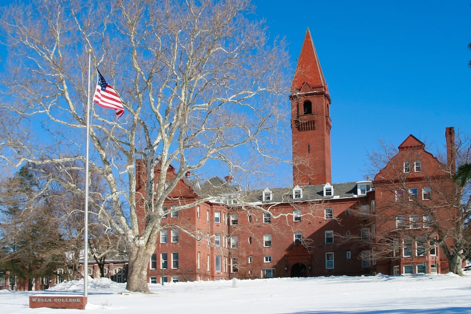 A red brick building with a tall tower and a flagpole with an American flag.