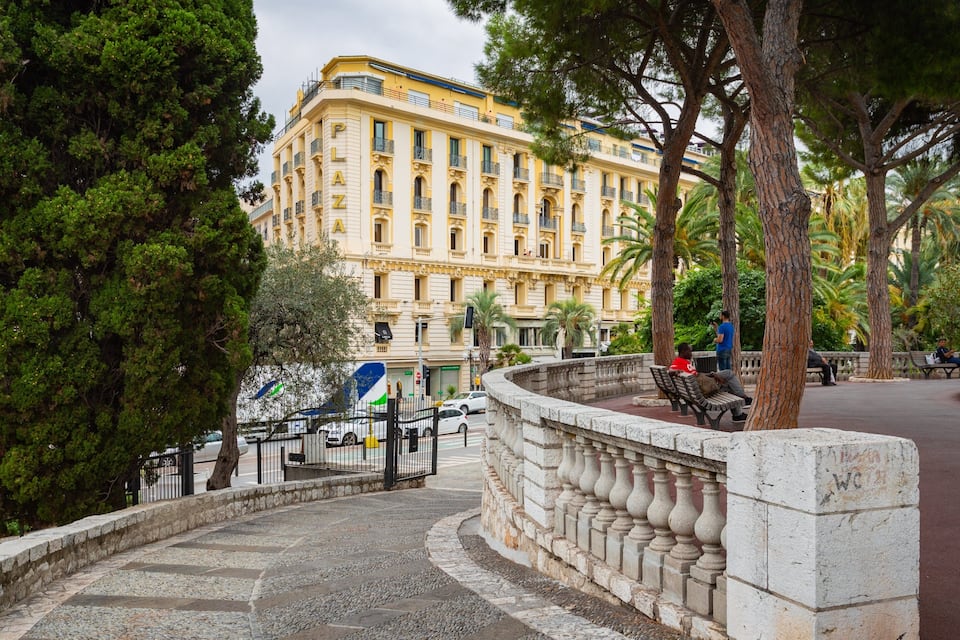 A historic building with ornate architecture, a stone pathway, and lush greenery.