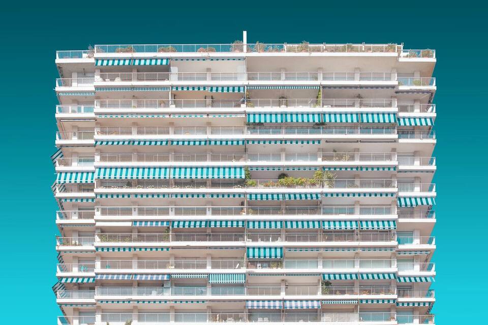 Un edificio de varios pisos con balcones y toldos a rayas.
