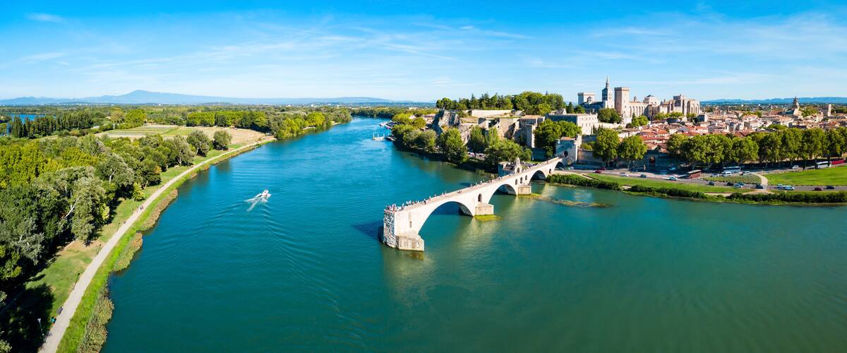 A river with a bridge, a castle, and a cityscape in the background.