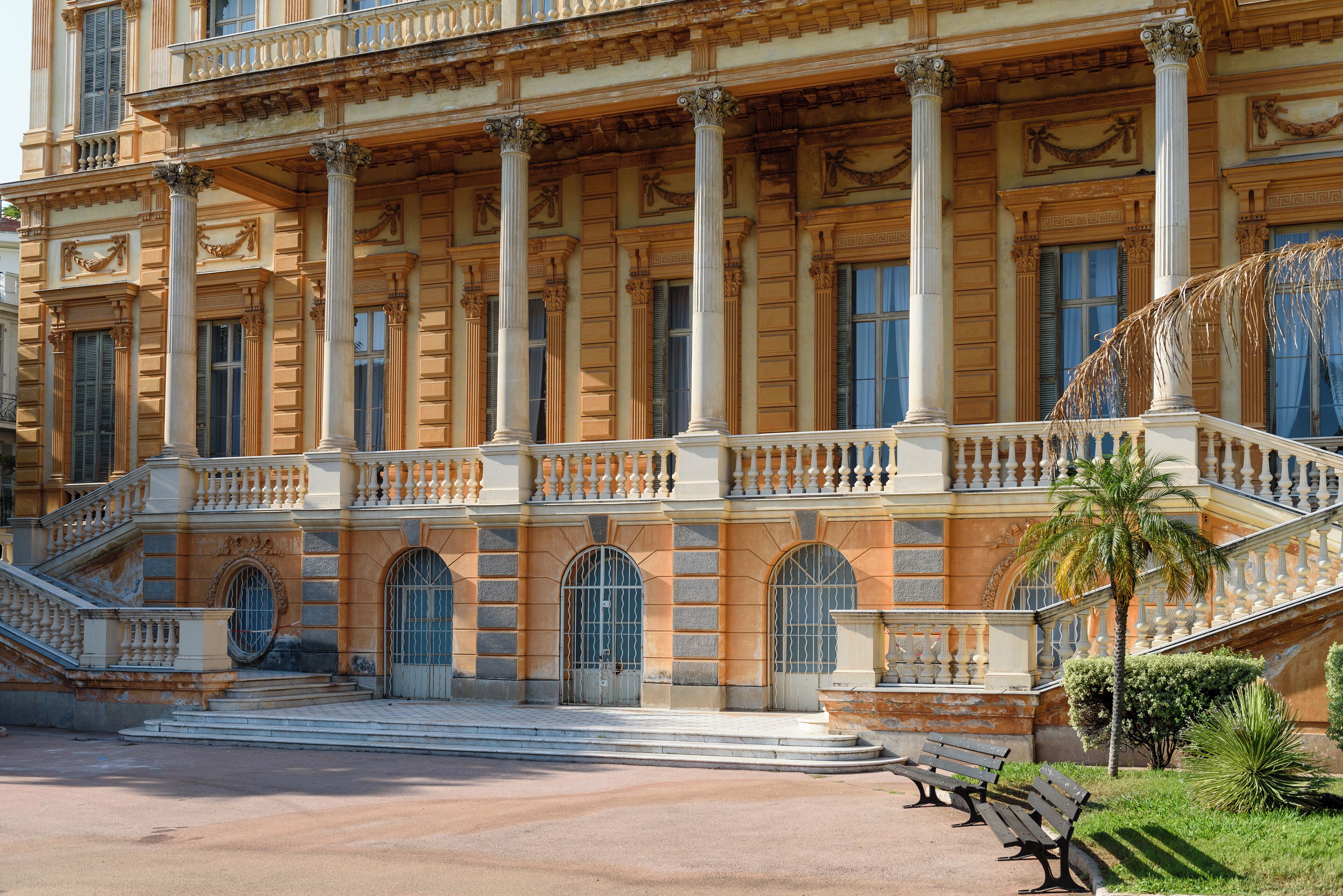 A grand building with classical architecture, featuring columns, arched windows, and a staircase.