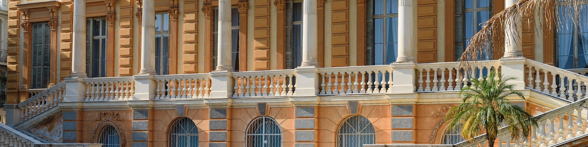 A grand building with classical architecture, featuring columns, arched windows, and a staircase.