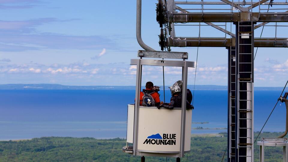 A cable car with the logo "Blue Mountain" against a backdrop of a lake and distant land.