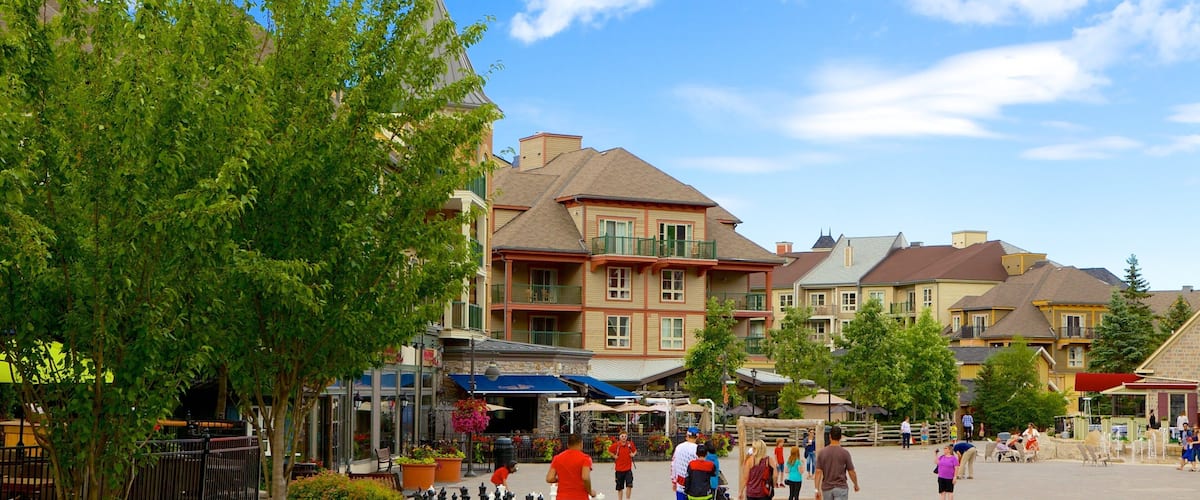 A pedestrian area with people walking, a chessboard, and buildings with balconies.