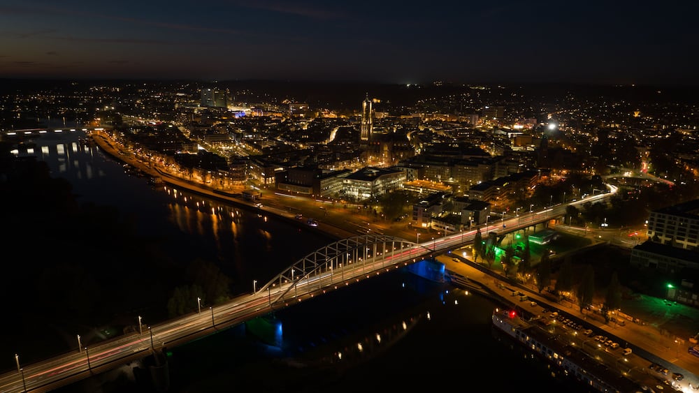 Arnhem city in the Netherlands by night Aerial drone. City center, rhine river and church, Eusebiuskerk, john frost bridge, skyline and infrastructure, city center.
