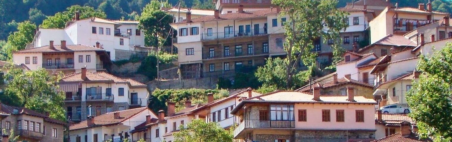 Un pueblo en una colina con edificios de tejados de teja anaranjada, incluyendo un hotel llamado 'HOTEL GALAXY'.