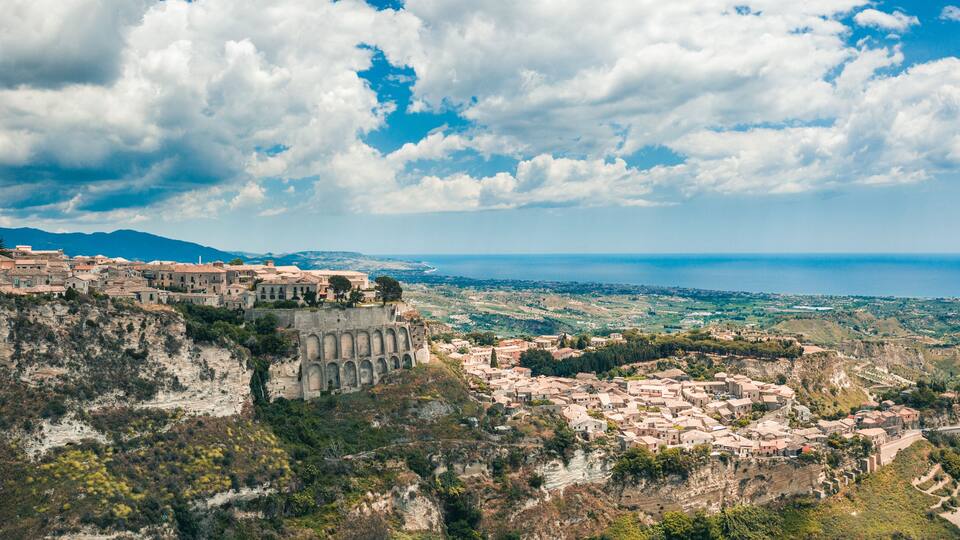A coastal town with historic architecture, a cliffside fortress, and a view of the sea.