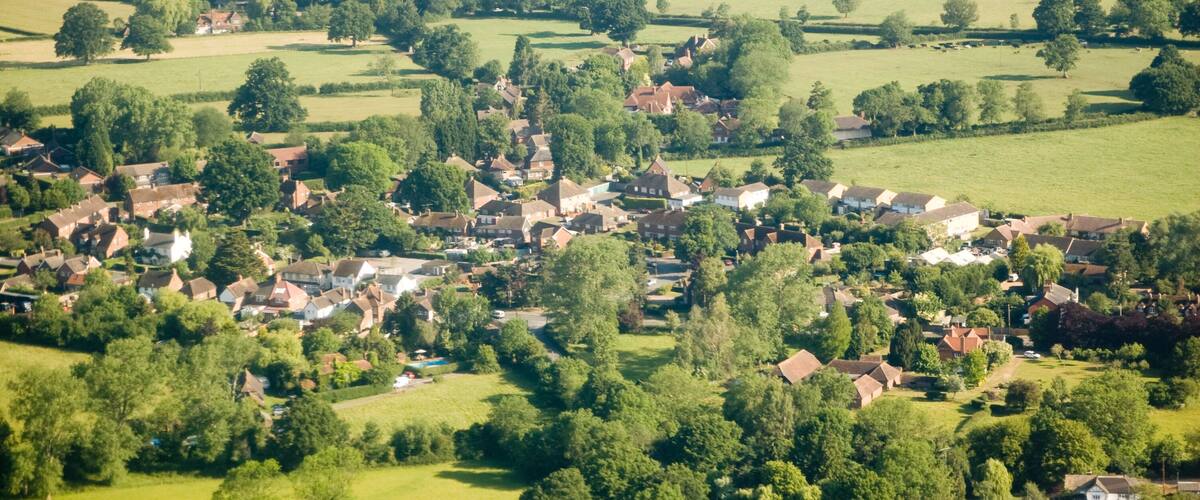 A rural village with houses, fields, and scattered trees.