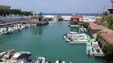 A marina with various boats docked, a pier, and buildings along the waterfront.