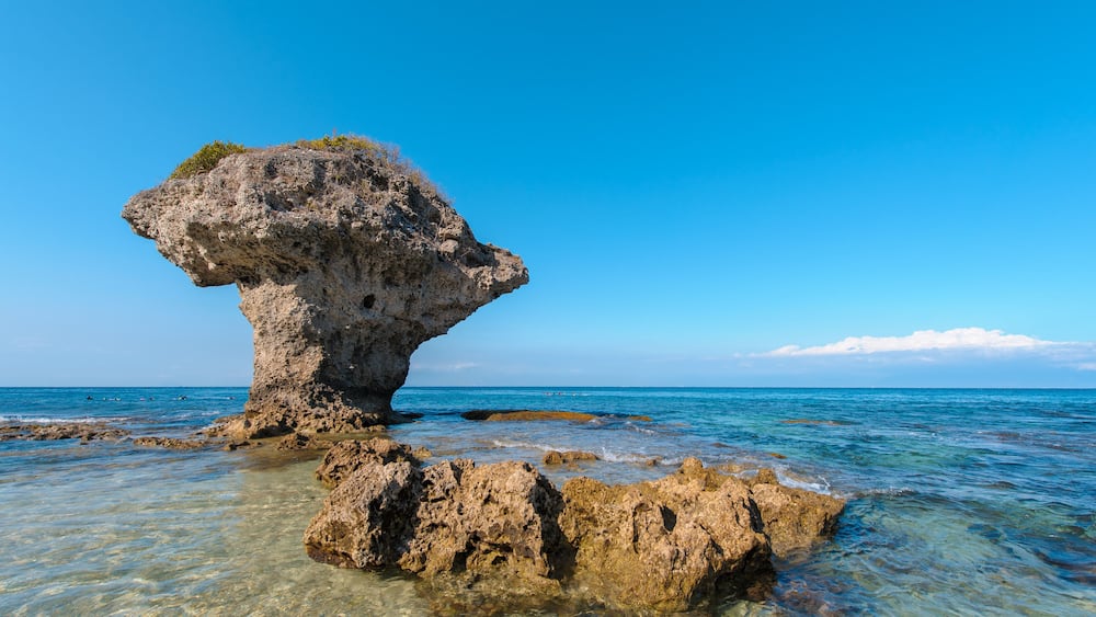 Un ciel d’un bleu limpide, une formation rocheuse et une mer calme.