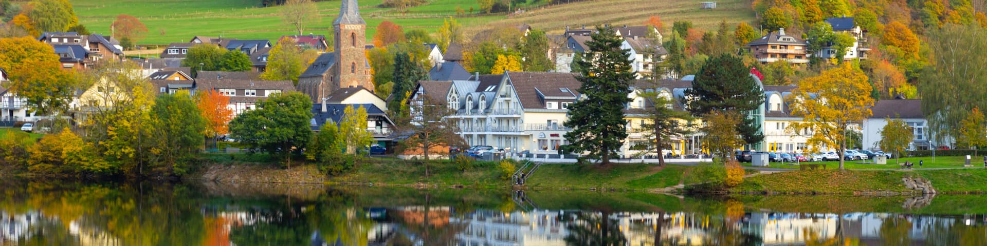 Beautiful german village with colorful foliage forest in the background and reflection in the Rursee lake, Einruhr, Simmerath