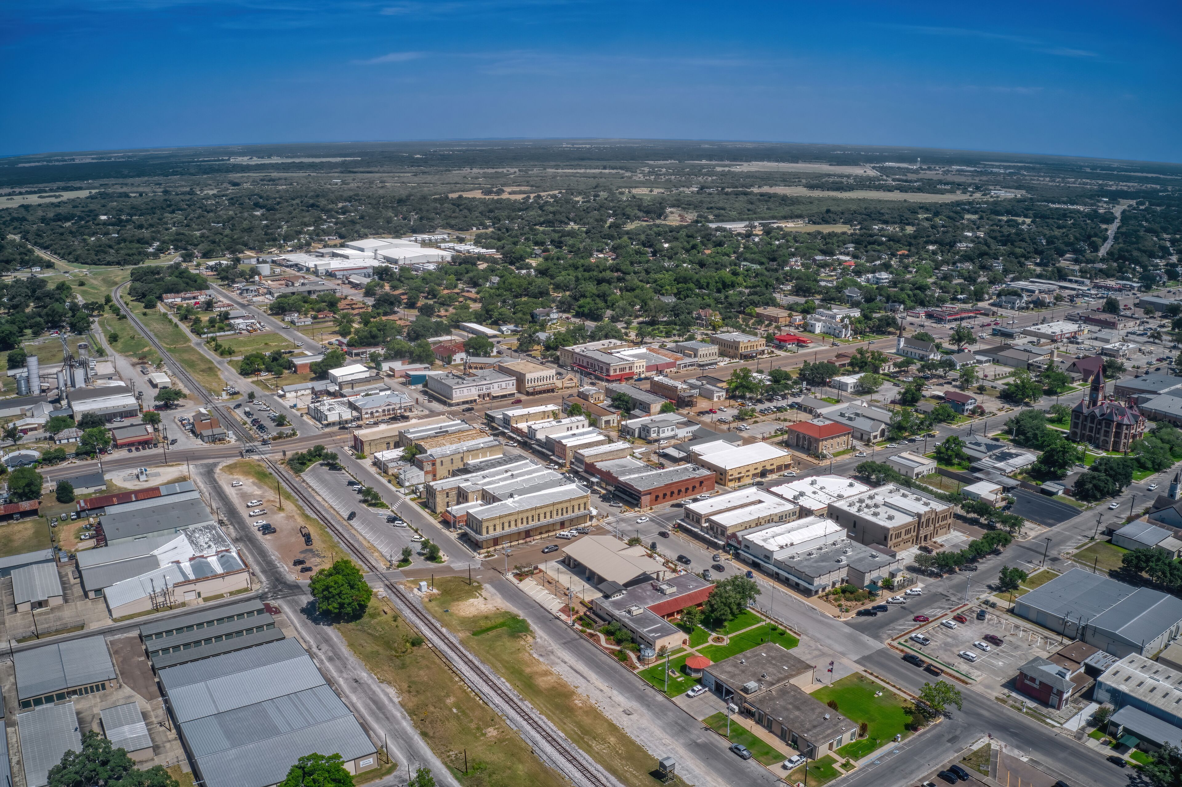 An aerial view of a town with industrial buildings, roads, and surrounding greenery.