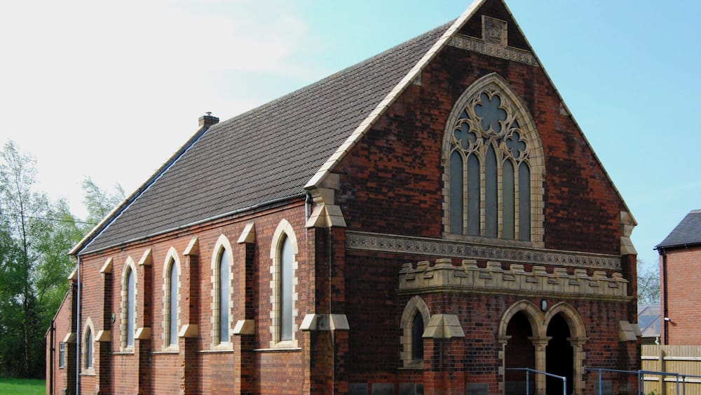 A brick church with a steep gabled roof and pointed arch windows.