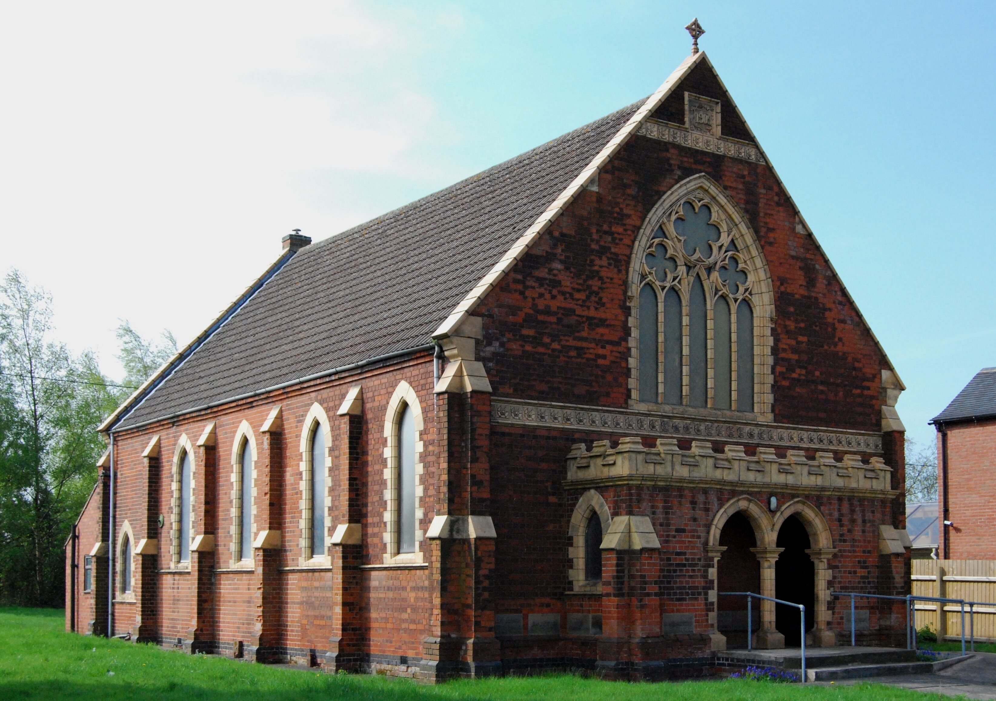 A brick church with a steep gabled roof and pointed arch windows.