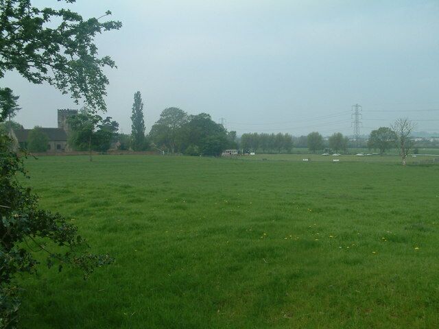 Um campo gramado com um edifício ao fundo.