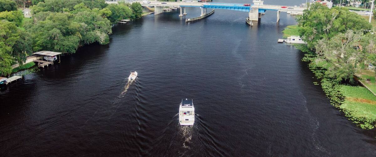 A river with a bridge, boats, and surrounding greenery.