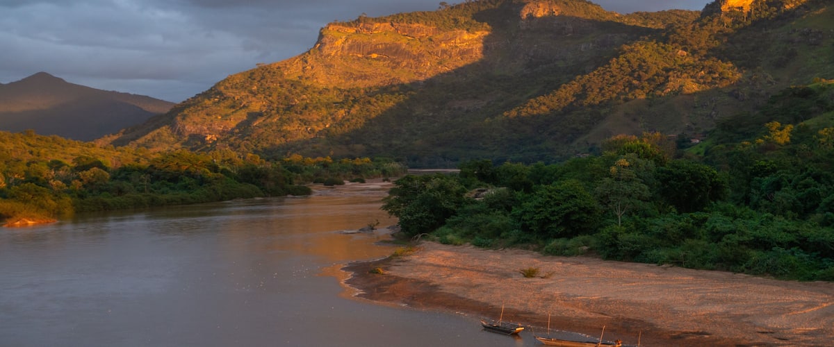 A river winding through a mountainous landscape with boats on the shore.