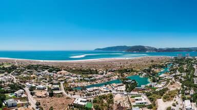 Aerial drone panoramic view of Troia, a peninsula located in Grandola Municipality, next to Sado River estuary, with Arrabida mountain range on left, Alentejo, Portugal