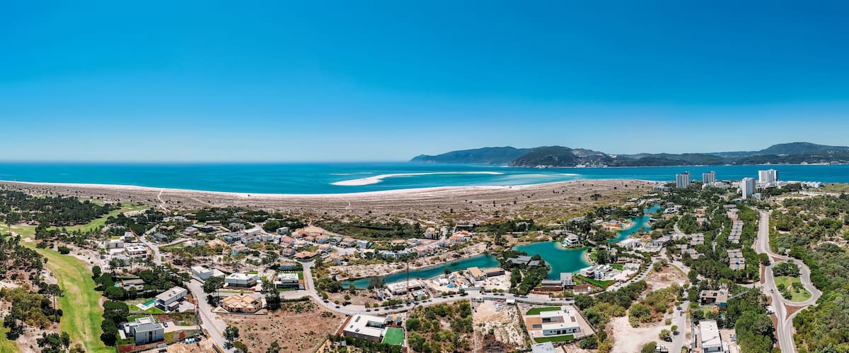 A coastal town with a beach, turquoise waters, and a mix of residential and commercial buildings.
