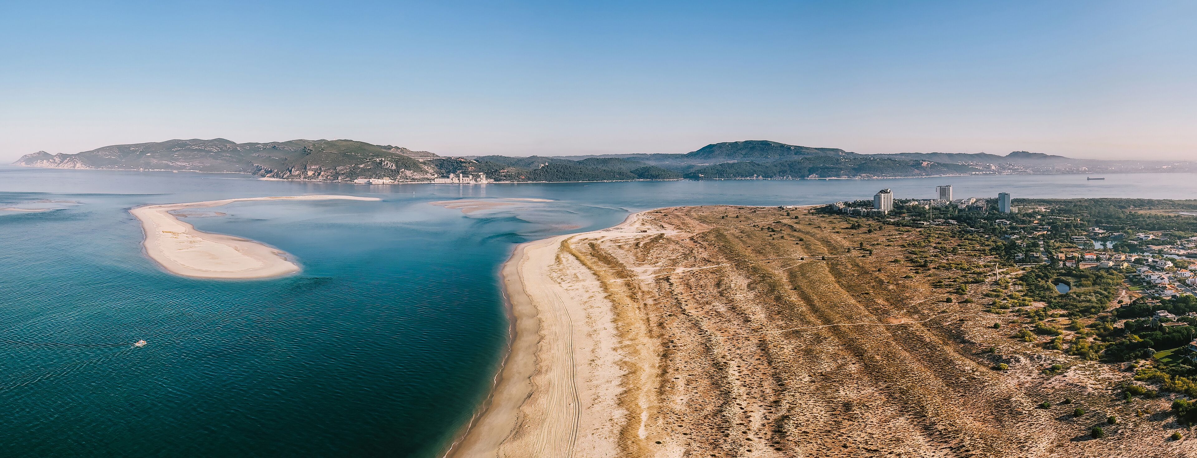 Aerial drone panoramic view of Troia, a peninsula located in Grandola Municipality, next to Sado River estuary, with Arrabida mountain range on left, Alentejo, Portugal