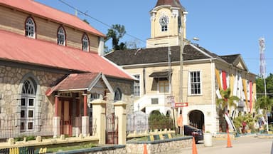 Un bâtiment historique doté d’une tour horlogée, de murs en pierre et d’une structure surmontée d’un toit rouge.