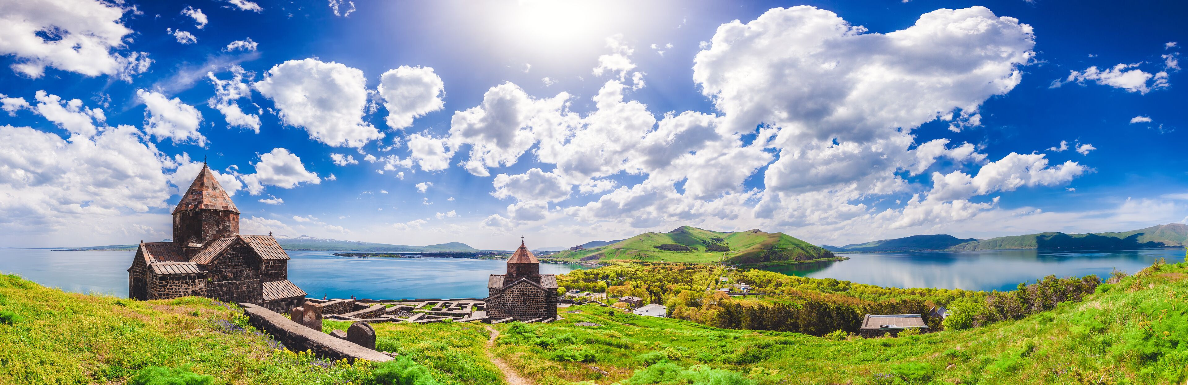 A coastal landscape with a church, a stone building, and a body of water.