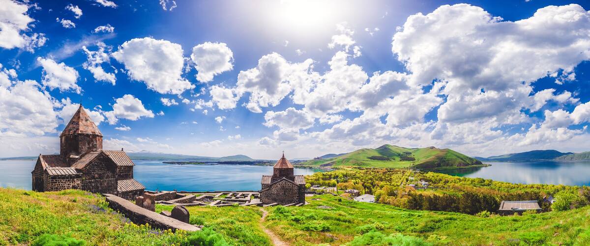 A coastal landscape with a church, a stone building, and a body of water.