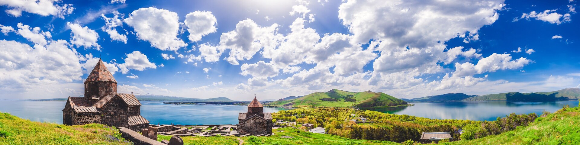 A coastal landscape with a church, a stone building, and a body of water.