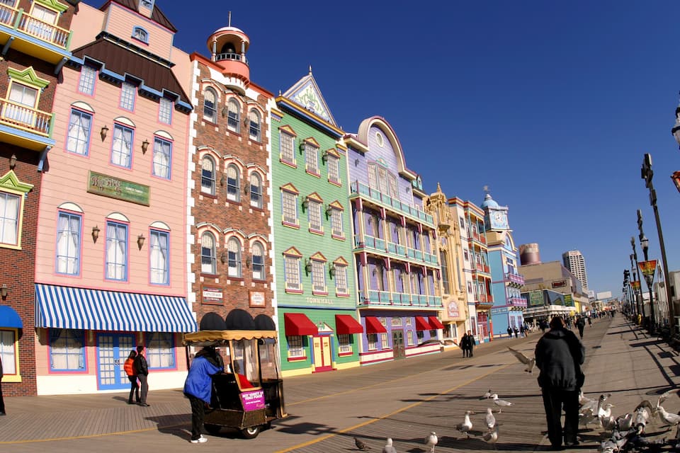 Un muelle colorido con edificios antiguos, un carrusel y gaviotas.