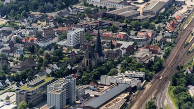 An aerial view of a city with dense housing, a prominent church, and railway tracks.