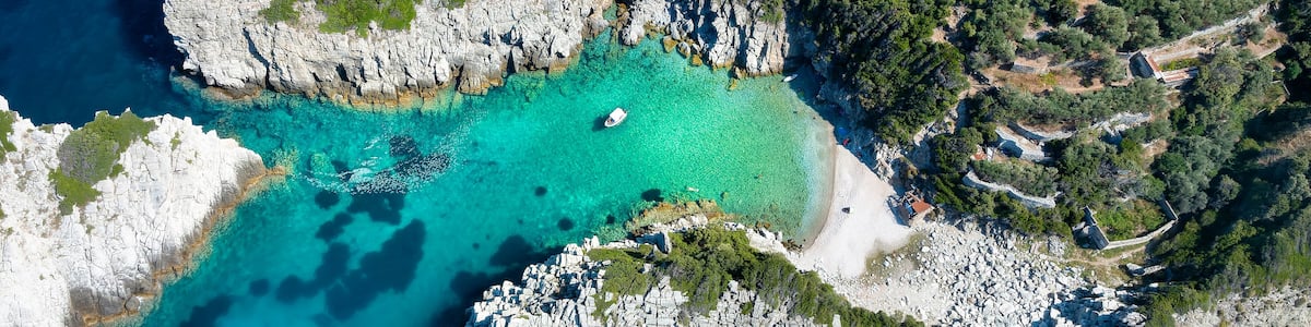 A coastal landscape with rocky cliffs, clear turquoise waters, and dense greenery.