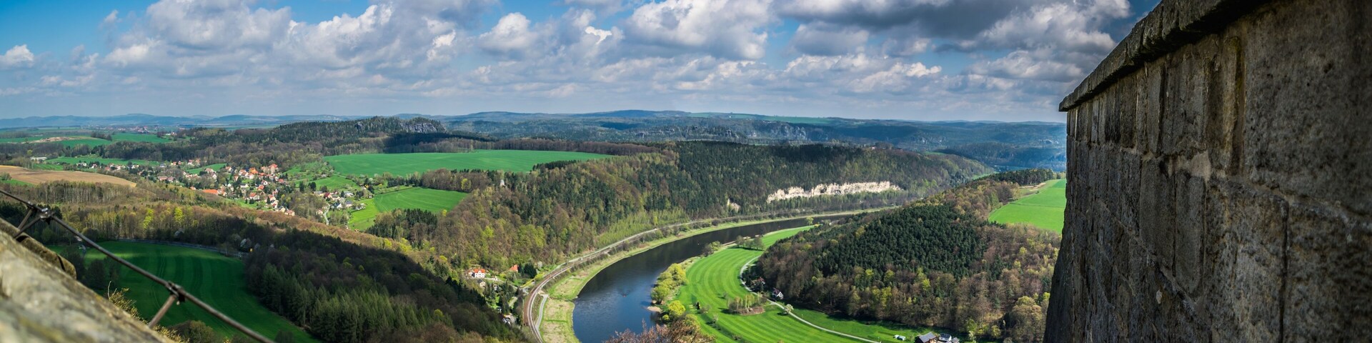 Un río serpentea por un valle con campos verdes y un pueblo.