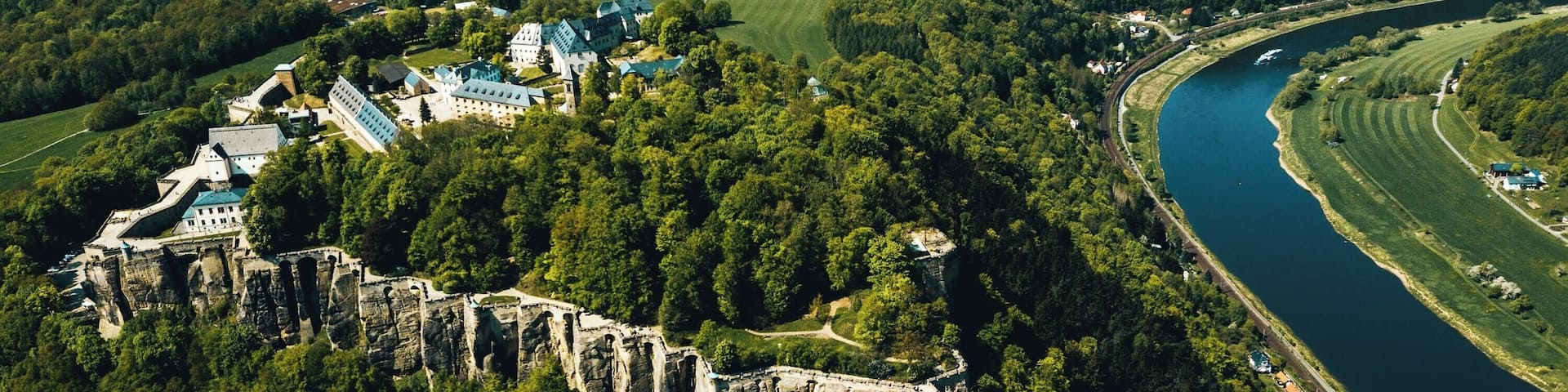 A castle surrounded by forest and a river.
