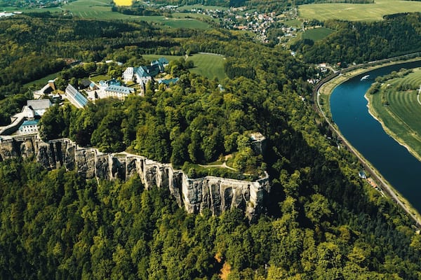 Eine Burg, umgeben von Wald und Fluss.
