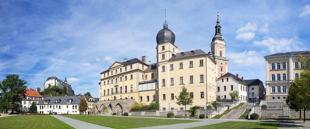 A historic building with a prominent tower and dome, surrounded by well-maintained lawns and a clear blue sky.