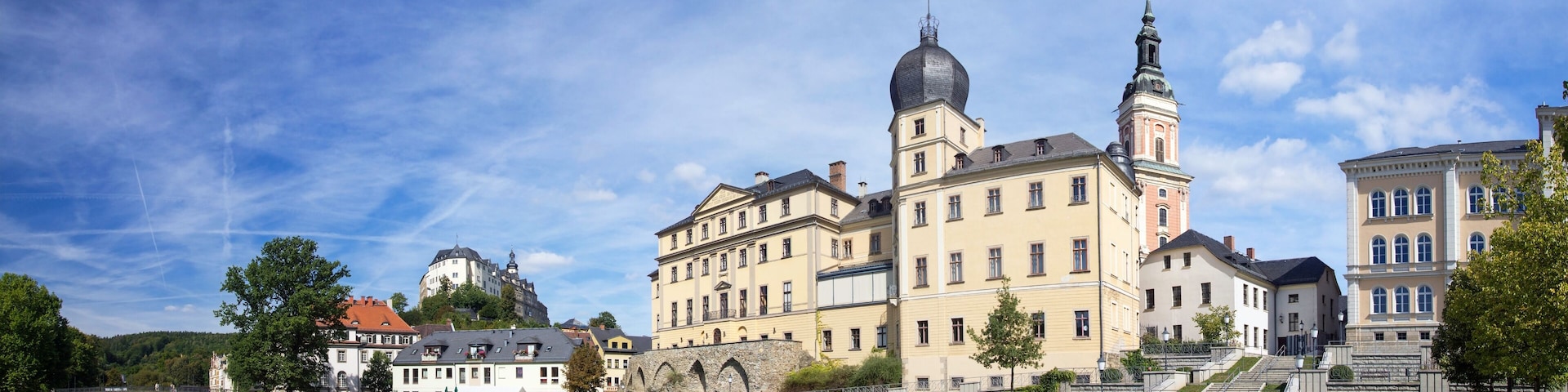 A historic building with a prominent tower and dome, surrounded by well-maintained lawns and a clear blue sky.