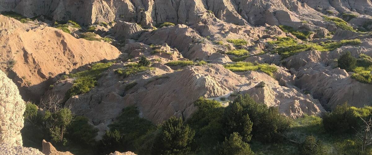 Un extenso paisaje de colinas escarpadas y erosionadas, con zonas de vegetación verde.