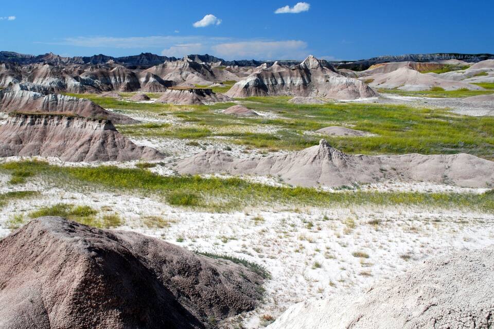 Een landschap met ruige, kleurrijke rotsformaties en schaarse groene begroeiing.