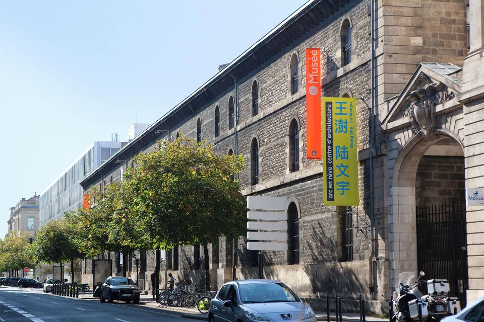 Un edifici històric amb pancartes grans i un carrer arbrat.
