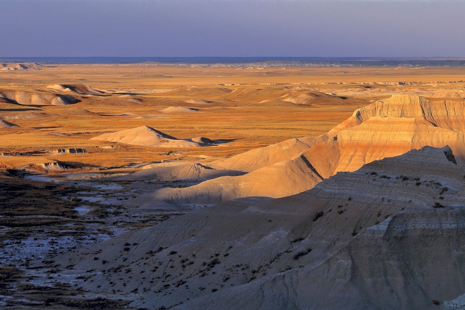 A vast, rugged landscape with prominent sandstone formations and a distant horizon.