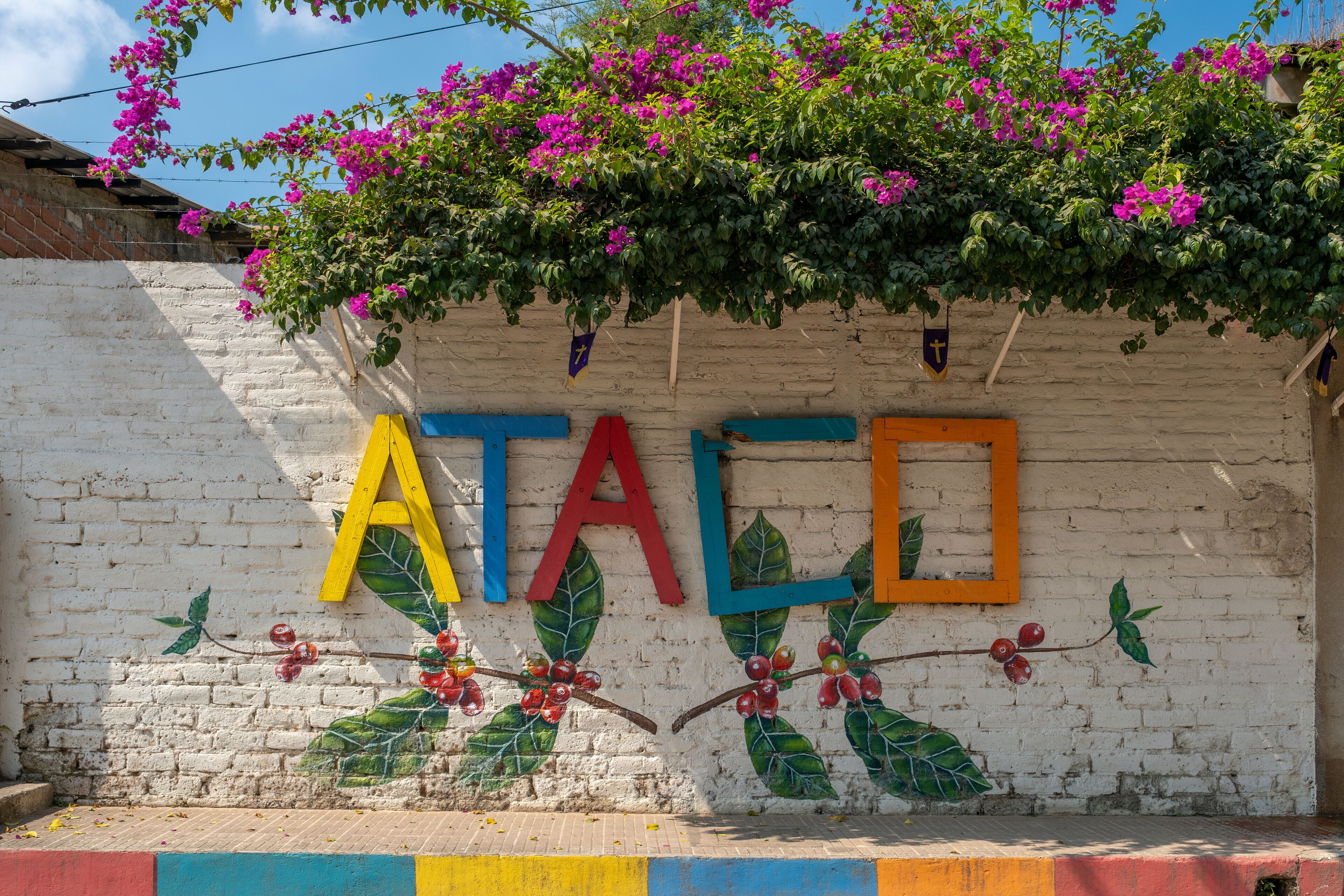 Sign Ataco made of colorful painted wooden planks on the brick fence in a small tourist town in coffee region. Concepcion De Ataco, El Salvador.