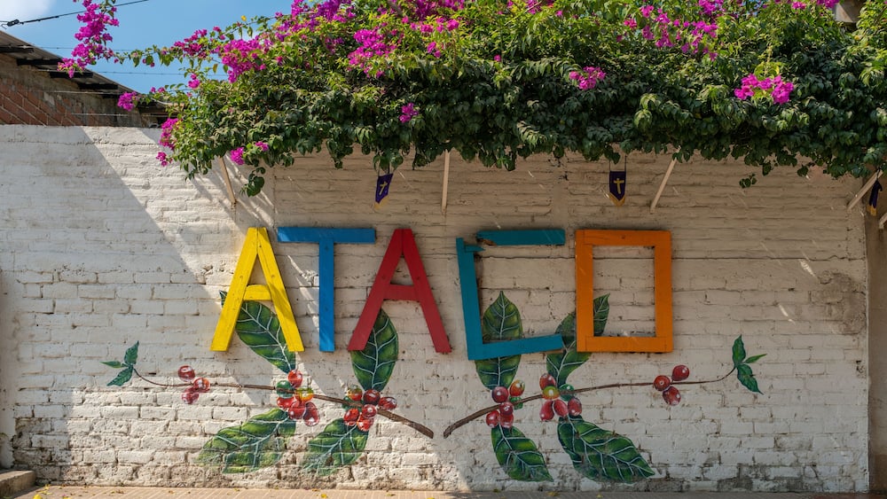 Sign Ataco made of colorful painted wooden planks on the brick fence in a small tourist town in coffee region. Concepcion De Ataco, El Salvador.