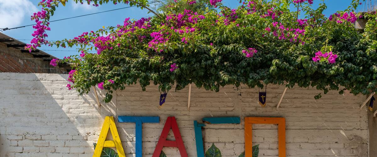 Sign Ataco made of colorful painted wooden planks on the brick fence in a small tourist town in coffee region. Concepcion De Ataco, El Salvador.