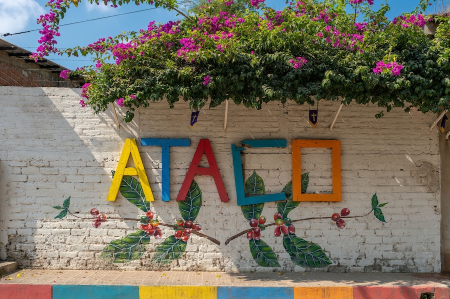 Sign Ataco made of colorful painted wooden planks on the brick fence in a small tourist town in coffee region. Concepcion De Ataco, El Salvador.