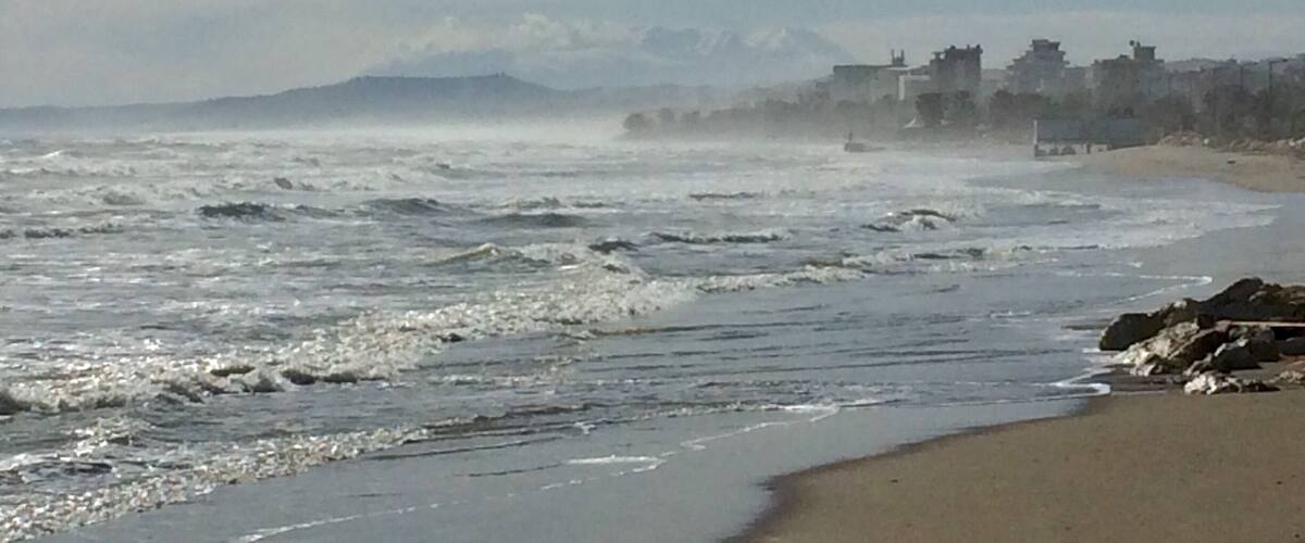 A beach with rough waves and a distant mountain range.