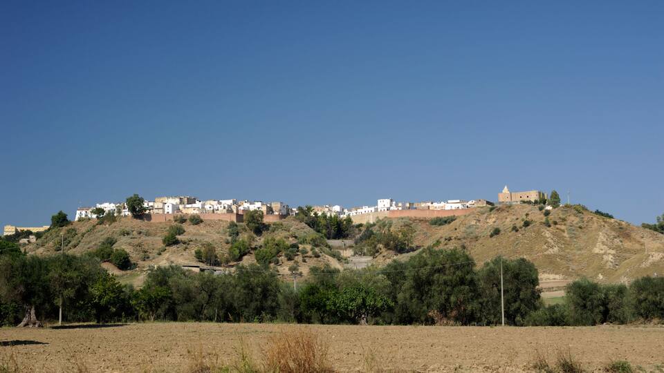 A hillside settlement with buildings and a prominent structure on top.