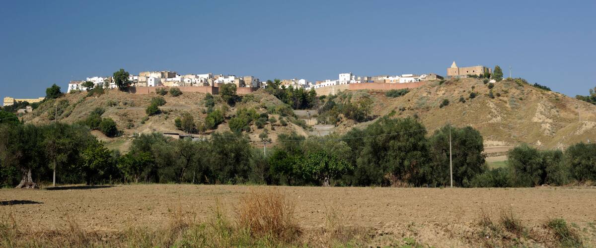 A hillside settlement with buildings and a prominent structure on top.