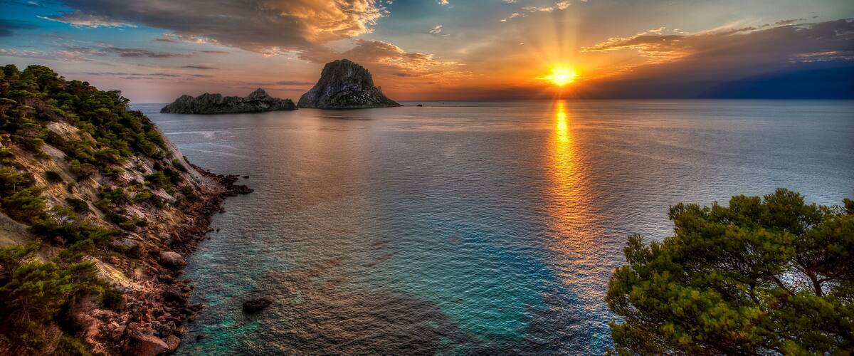 A sunset over a coastal landscape with rocky cliffs and a small island.